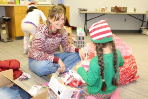 A picture of a student and volunteer going through gifts during Sugar Plum in 2022.