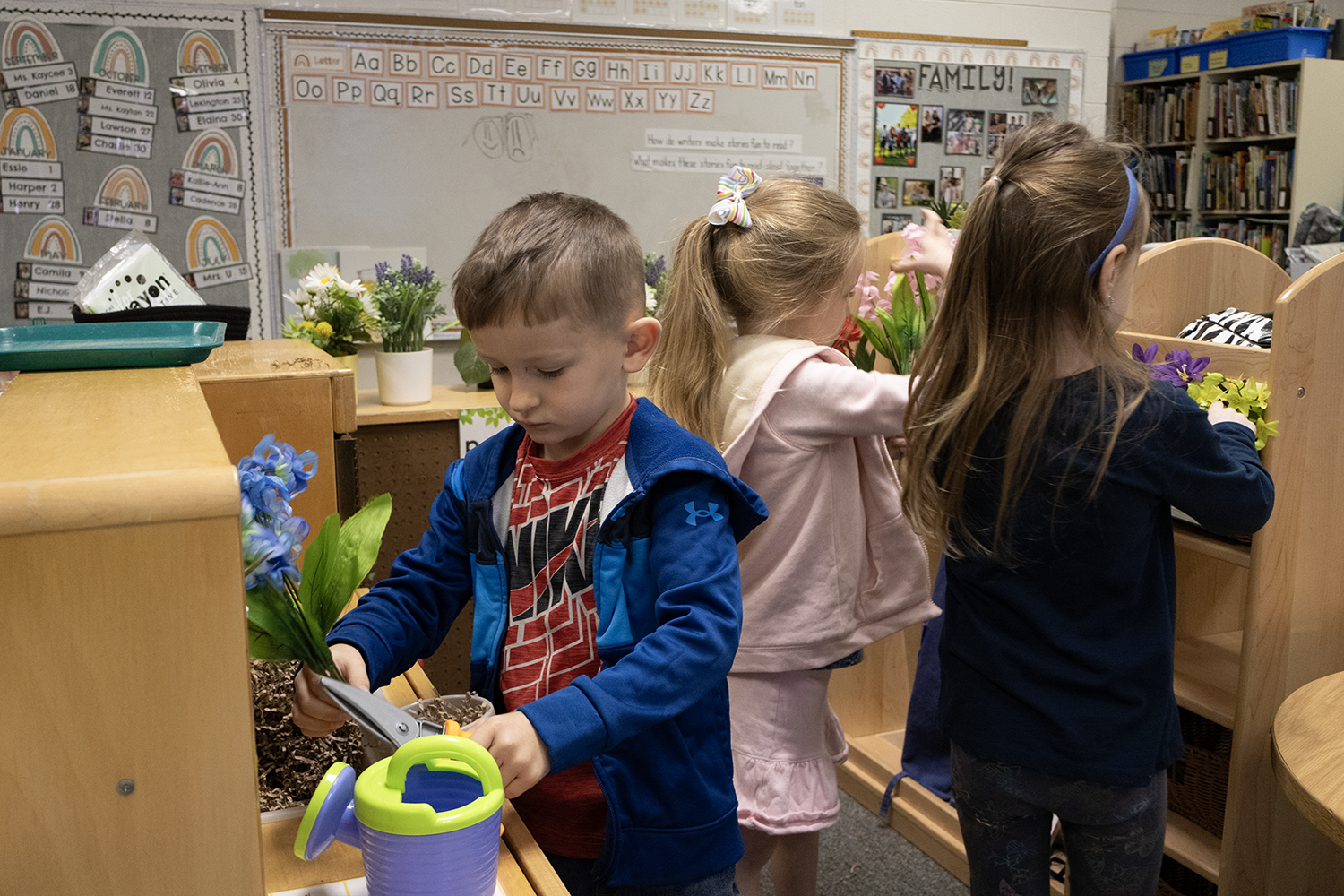 Three Pre-K students are planting spring flowers